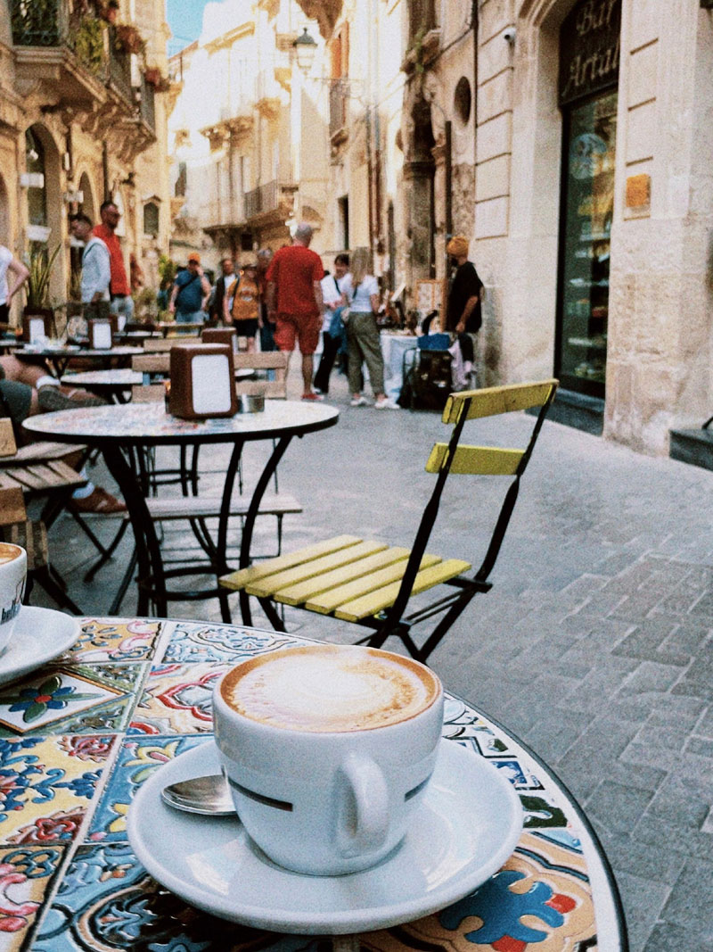 Caff� accogliente all'aperto in una strada di Siracusa con cappuccino e atmosfera vivace.