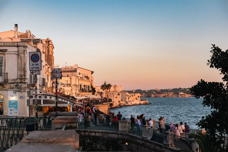 Incantevole tramonto sulla scenografica passeggiata di Siracusa, con vista sulla costa.